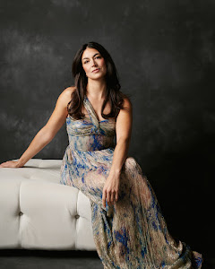 Editorial full-length portrait in a patterned dress against a dark studio background